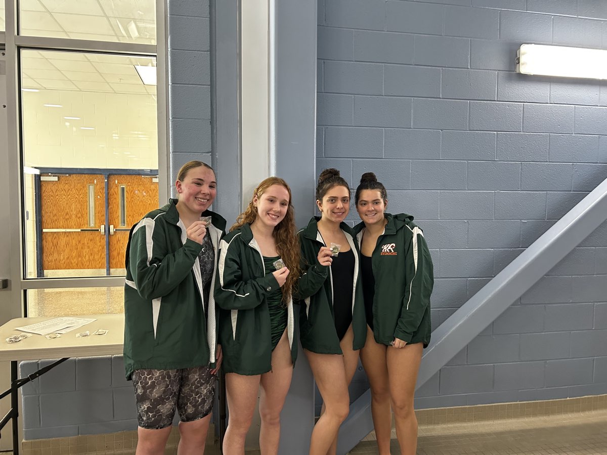 Four Kettle Run girls in team jackets holding up their medals